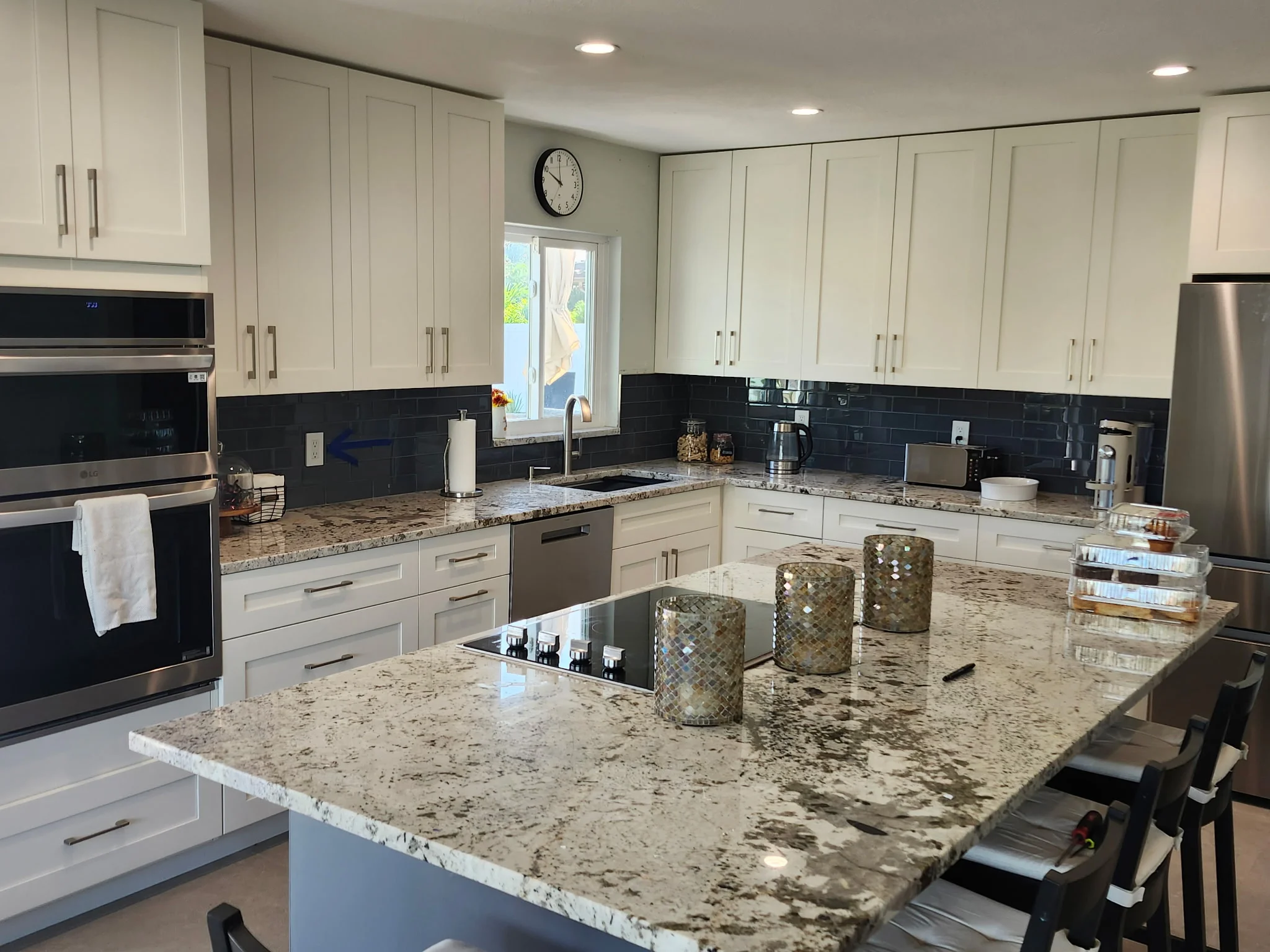 White cabinetry kitchen with granite countertops, black subway tile backsplash, and stainless steel appliances