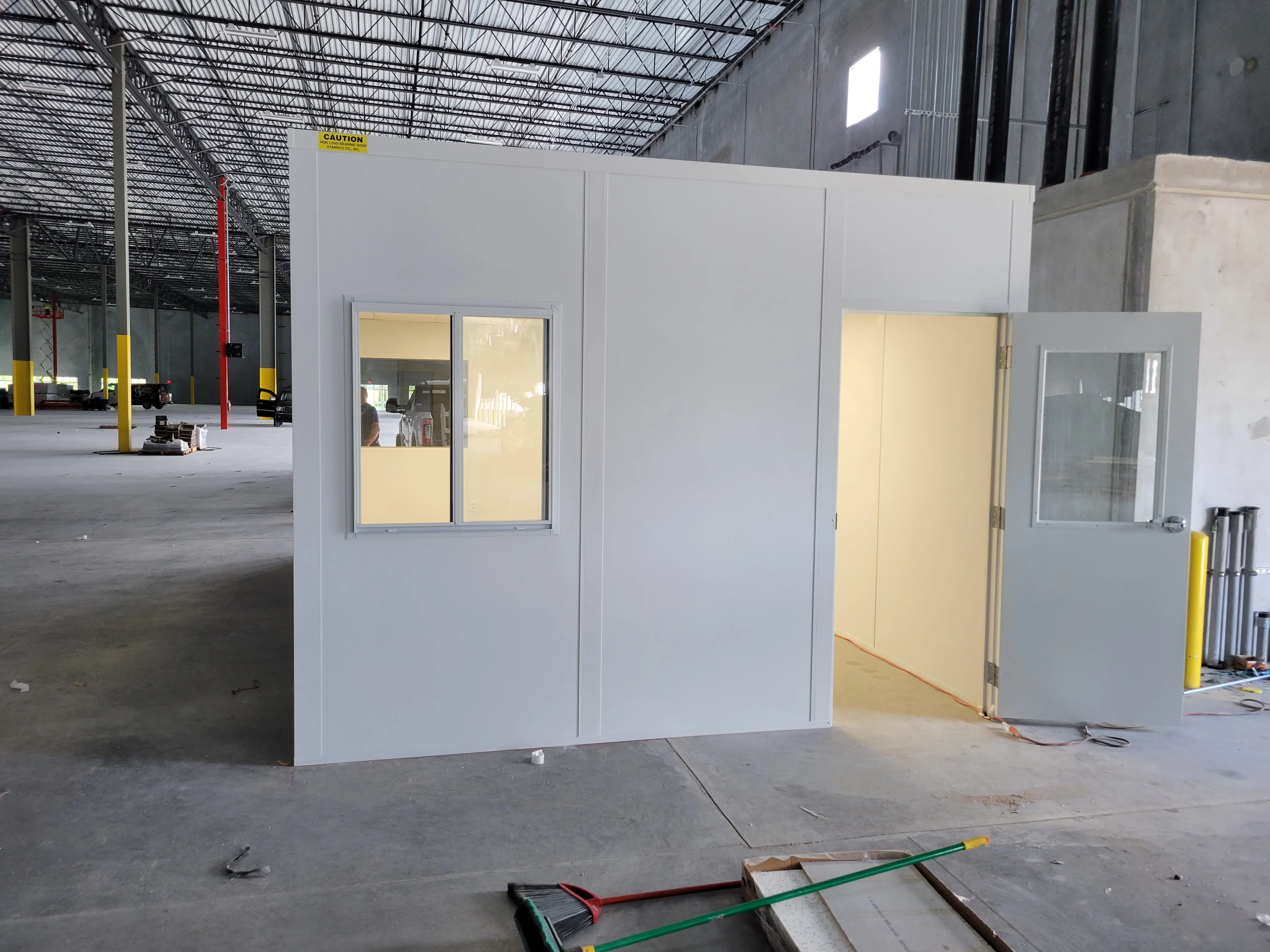 White drywall modular office with aluminum windows and entry door in industrial warehouse