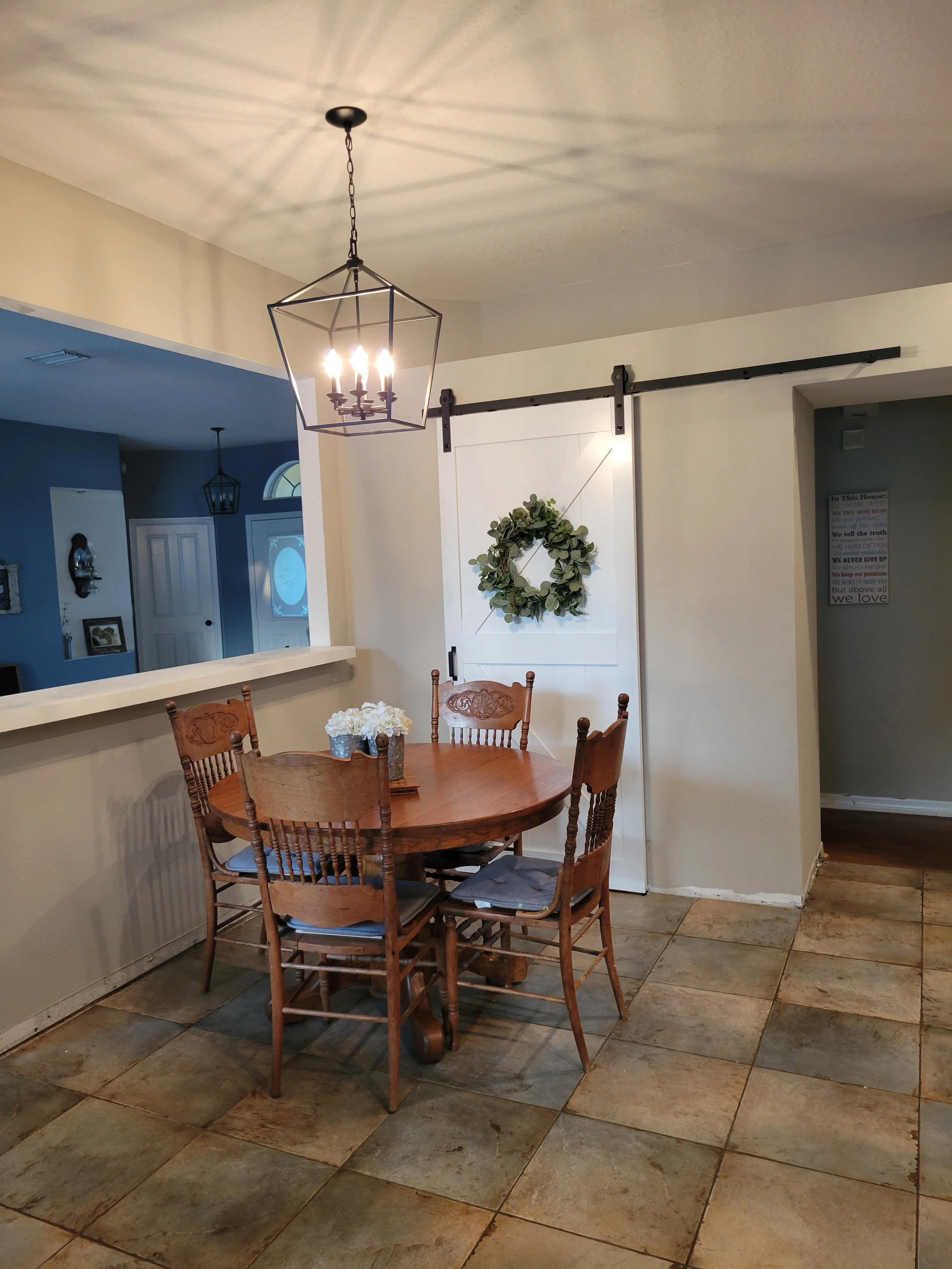 Dining nook with tile flooring, cream walls, blue accent wall, barn door, and pendant lighting