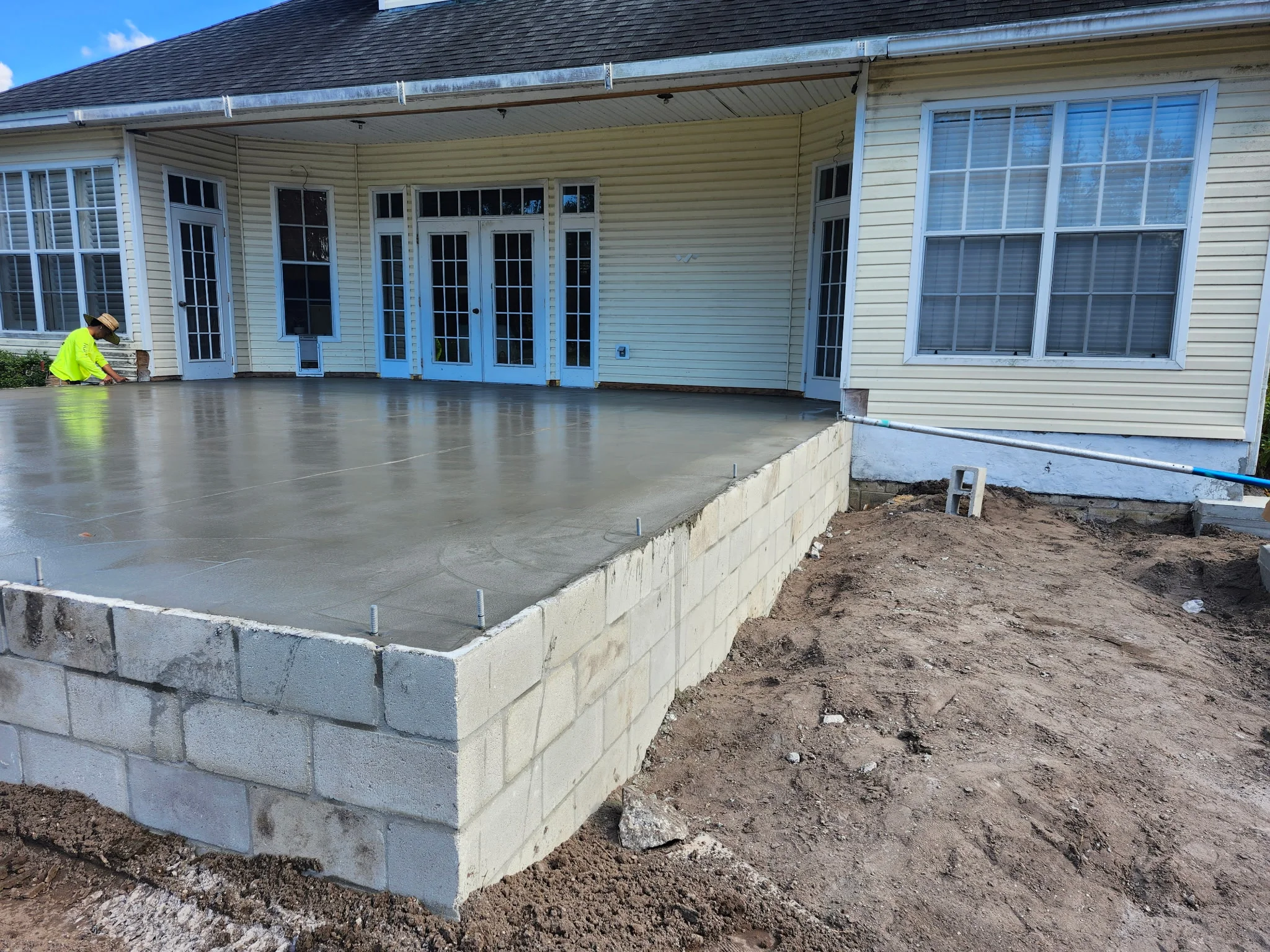 Freshly poured concrete patio with concrete block retaining wall foundation and site preparation