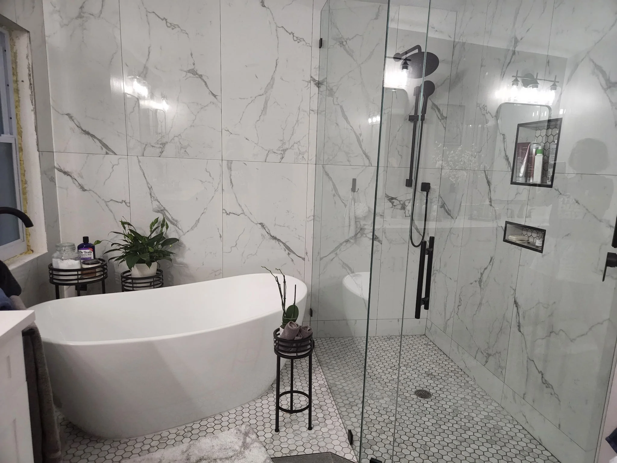 Marble tile bathroom with freestanding tub, frameless shower enclosure, and hexagonal floor tile