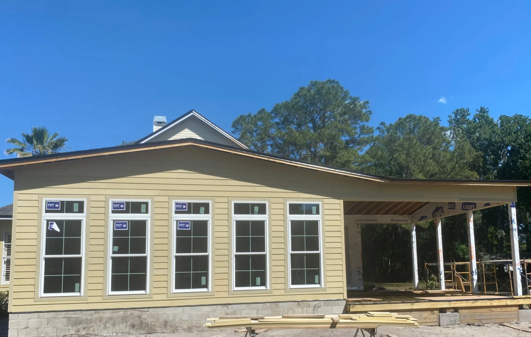 Five white double-hung windows in cream vinyl siding on new home construction with covered porch