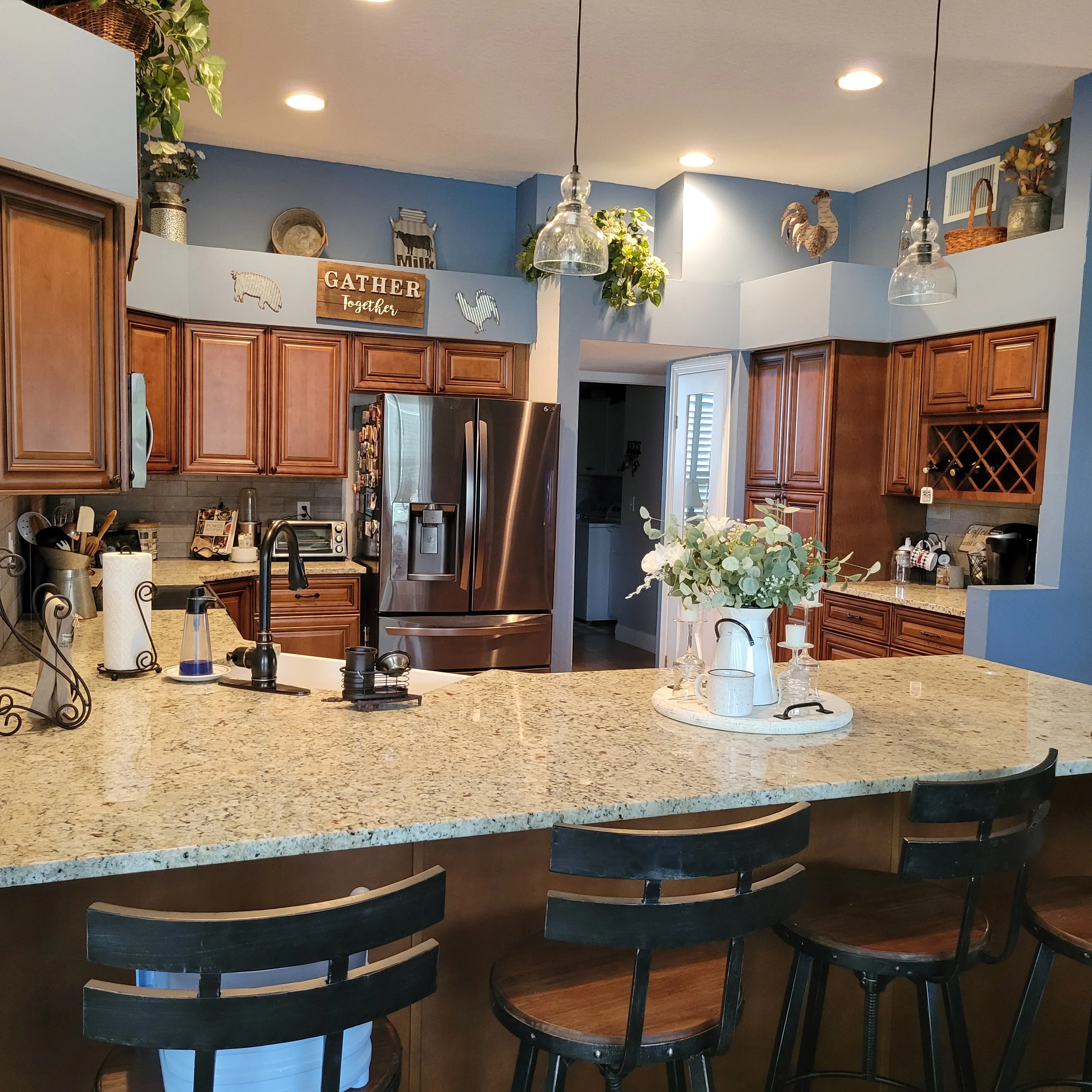 Kitchen with cherry cabinets, blue walls, quartz island countertop, and stainless steel appliances